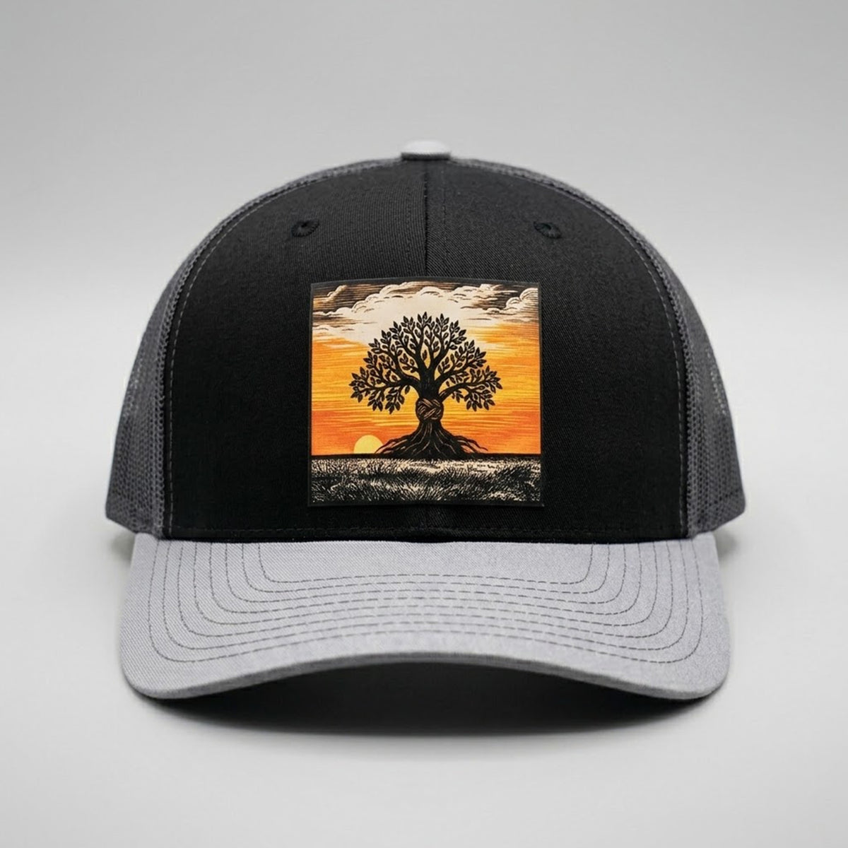 Graphe trucker hat in black and grey, front view, patch of a lone tree at sunset with exposed roots